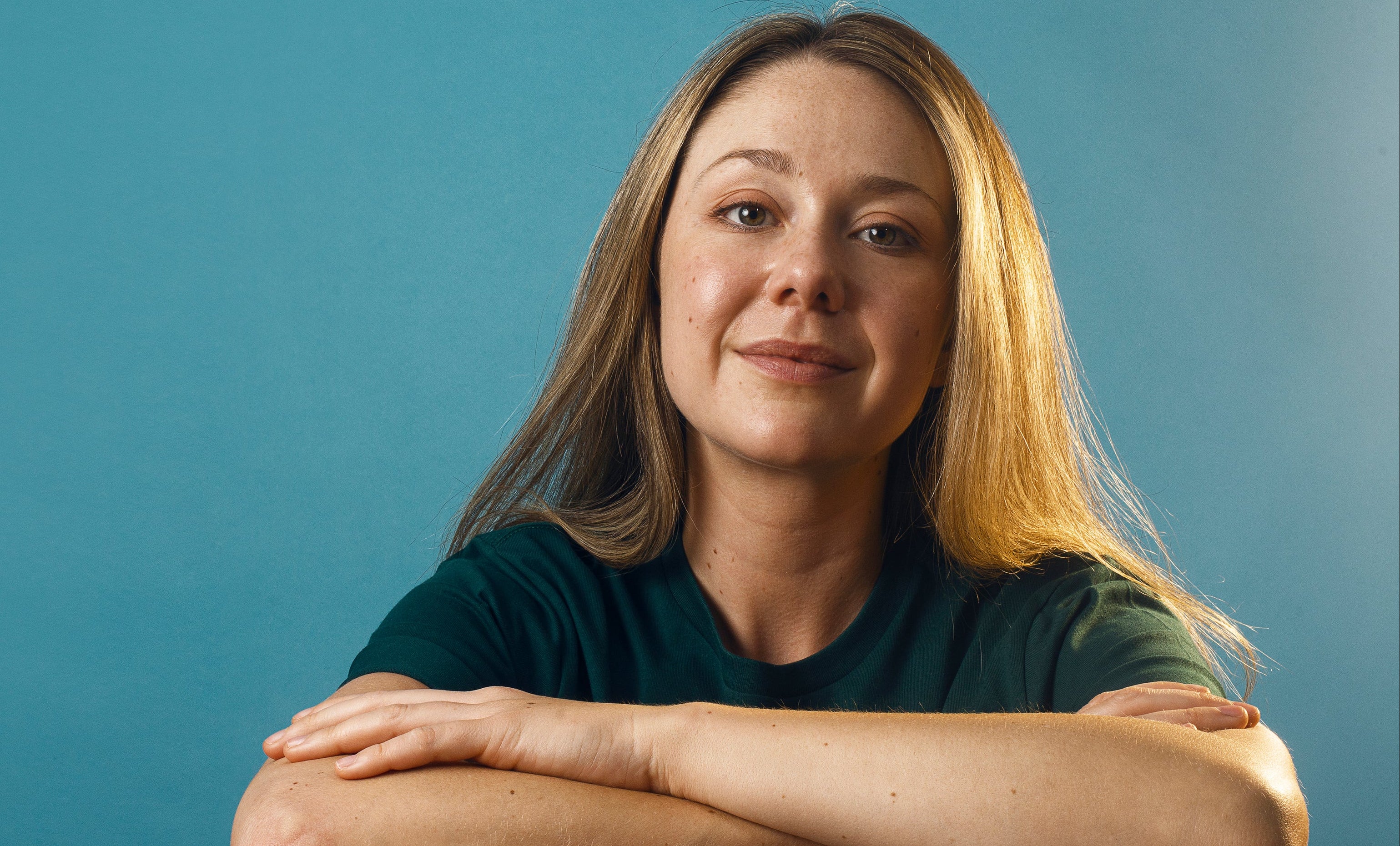 files/a-woman-in-a-plain-green-shirt-against-a-blue-backdrop.jpg